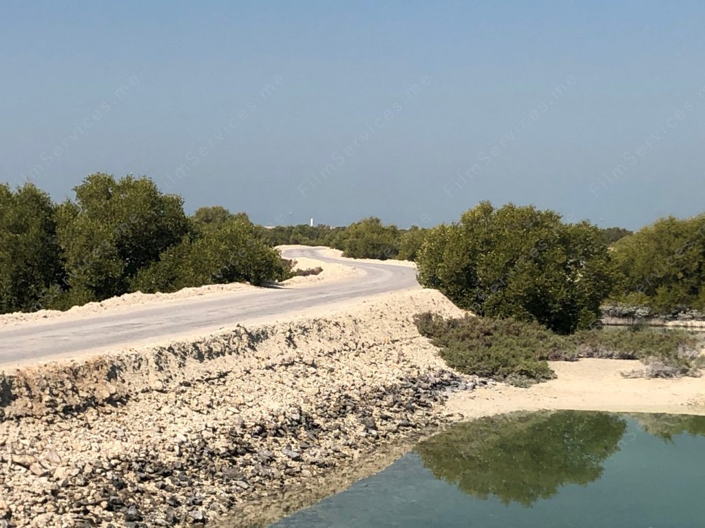 Picture of a dirt bridge over water. Abudhabi Film Location Mangrove, sand bridge and rustic road. A truly serene and picturesque scene that is sure to evoke a sense of peace and tranquility in anyone who beholds it.