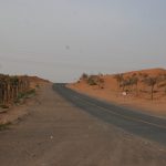 A picture of a desert road, captivating location showcases a twisty desert road that meanders through a tranquil landscape