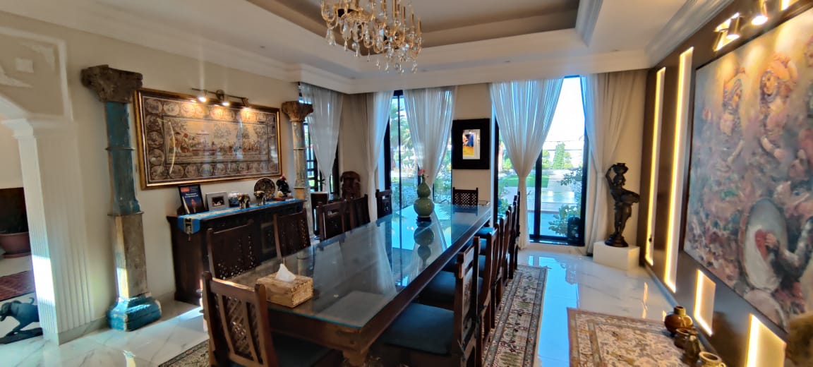 Dubai Dining Room Film Location 1 Primary image for Elegant Dubai dining room film location with 12-seater teak table, chandelier, garden views, and cinematic natural light for shoots.