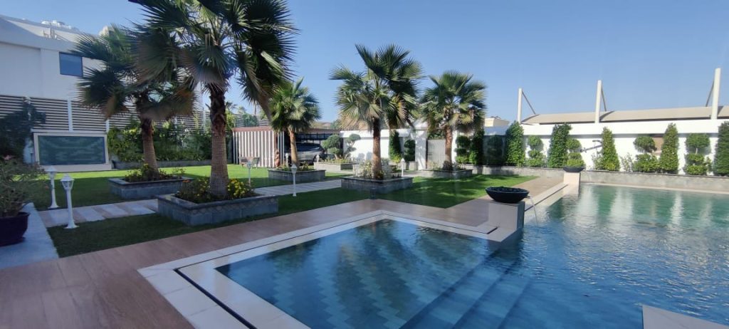 Primary picture of Elegant Dubai swimming pool film location with manicured gardens, palm trees, bougainvillea, stone walkways, and cinematic outdoor settings